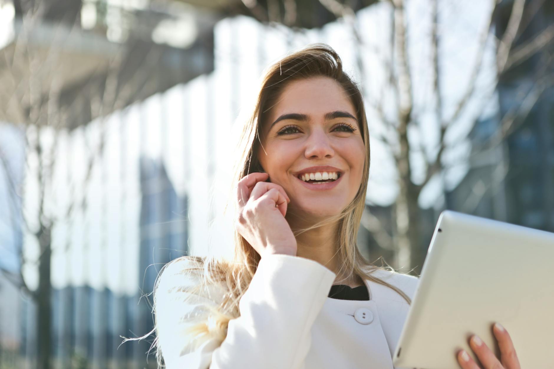 woman in white blazer holding tablet computer