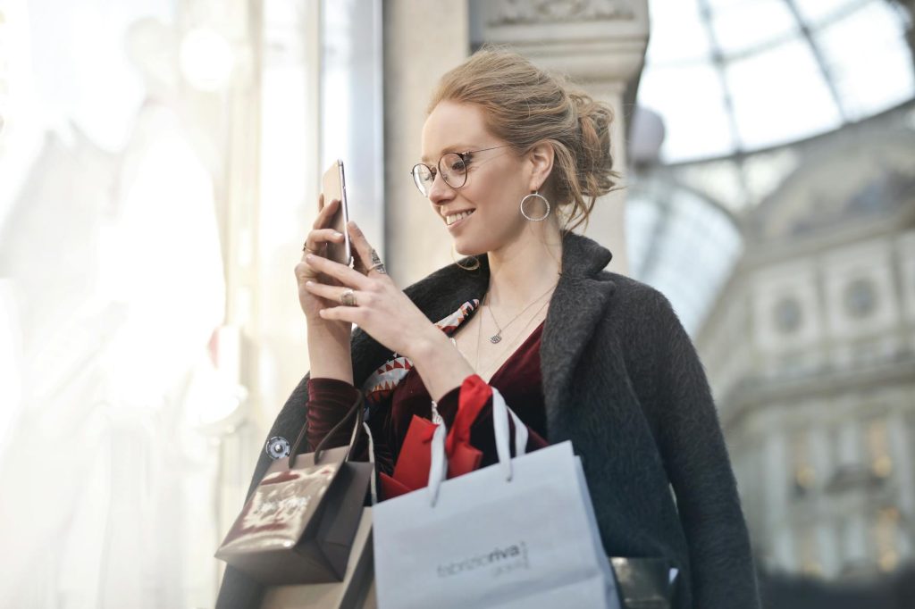 woman standing near wall holding phone