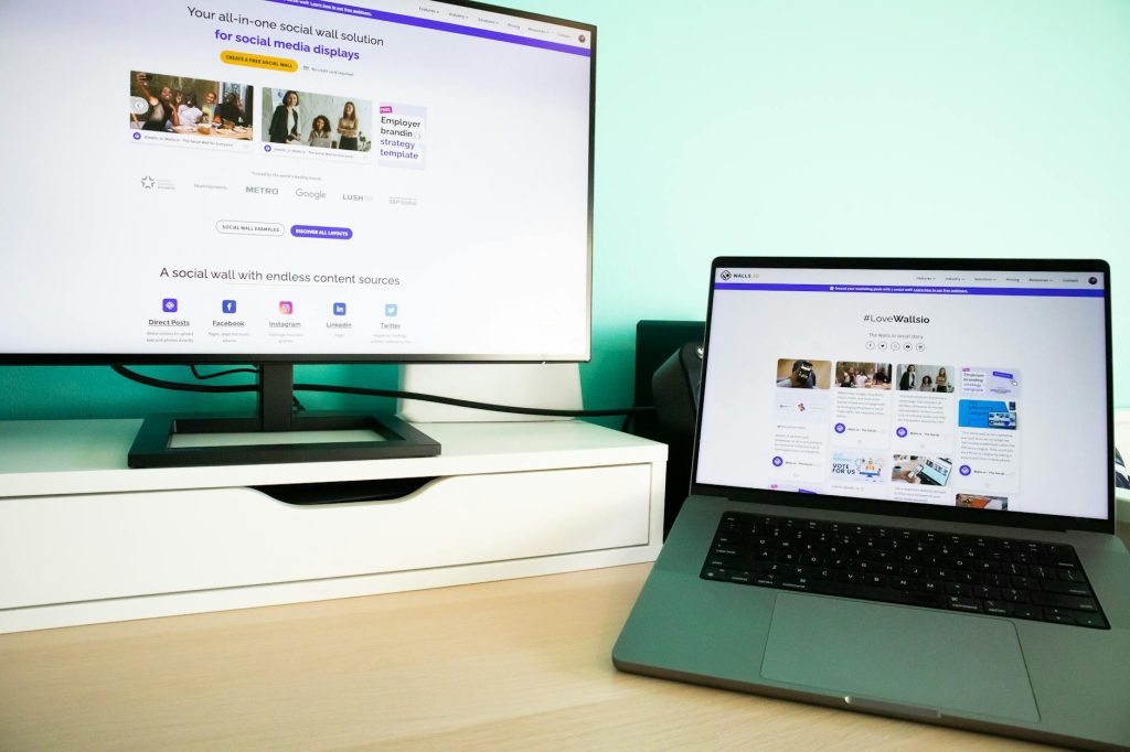 a desk with a laptop and monitor displaying websites